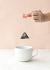Pyramid sachet held over white mug